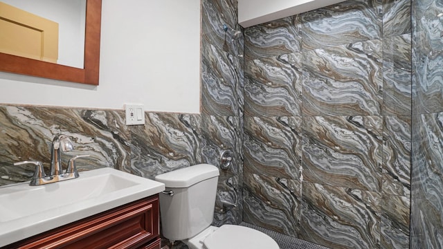 bathroom featuring vanity, toilet, and tile walls