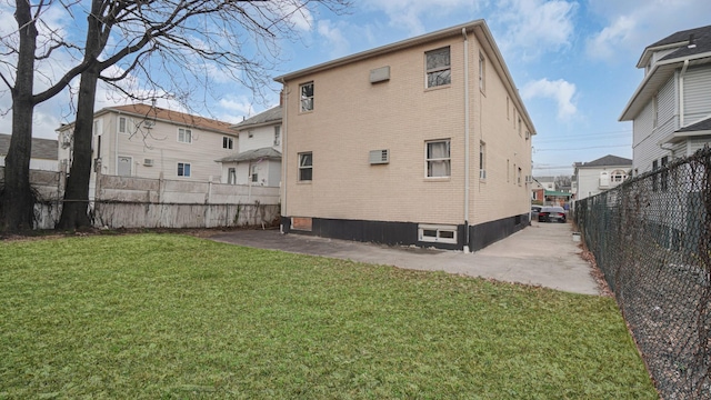 rear view of property with an AC wall unit and a lawn