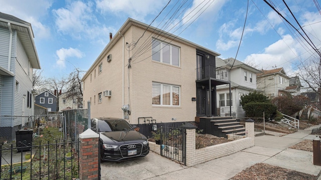 view of front of house featuring a wall mounted AC and a balcony