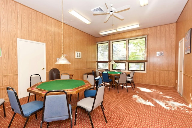 game room with ceiling fan, carpet, and wood walls