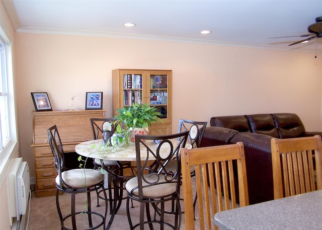 carpeted dining area featuring radiator, crown molding, and ceiling fan