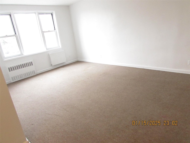 carpeted spare room featuring radiator heating unit