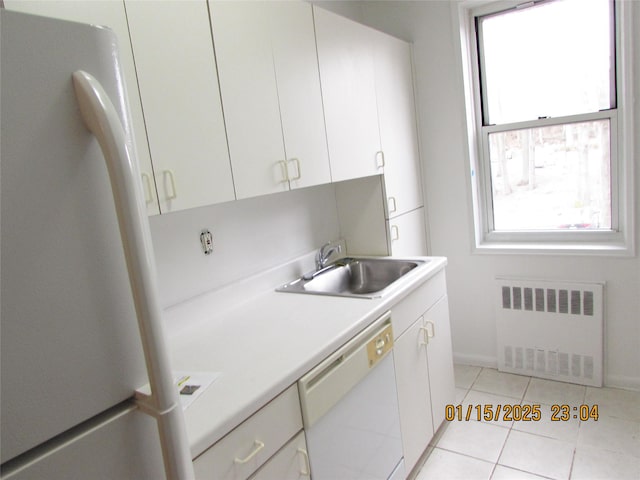 kitchen with white appliances, white cabinets, radiator heating unit, a healthy amount of sunlight, and sink