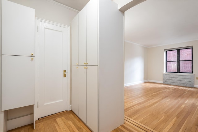 hallway with crown molding and light hardwood / wood-style flooring