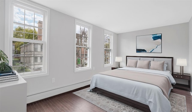 bedroom with dark hardwood / wood-style flooring and a baseboard heating unit