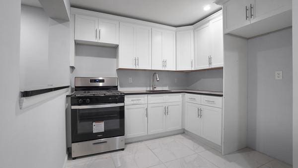 kitchen with sink, white cabinetry, and gas stove