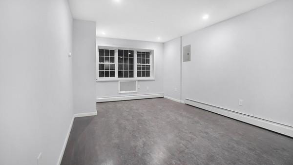 spare room featuring a baseboard heating unit, electric panel, and concrete flooring