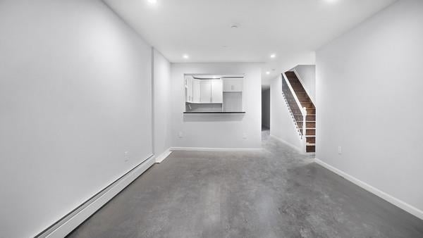 unfurnished living room featuring baseboard heating and concrete floors