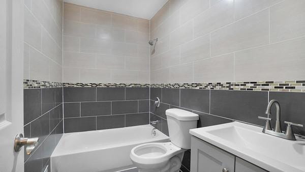 full bathroom featuring tiled shower / bath combo, toilet, and vanity