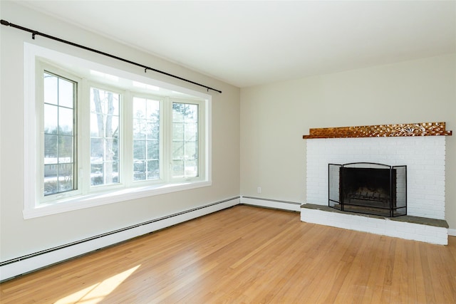 unfurnished living room featuring hardwood / wood-style floors, baseboard heating, and a brick fireplace