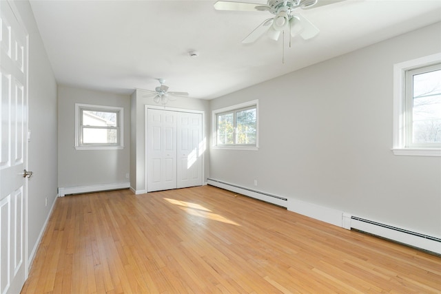 unfurnished bedroom with a closet, light hardwood / wood-style flooring, ceiling fan, and a baseboard heating unit