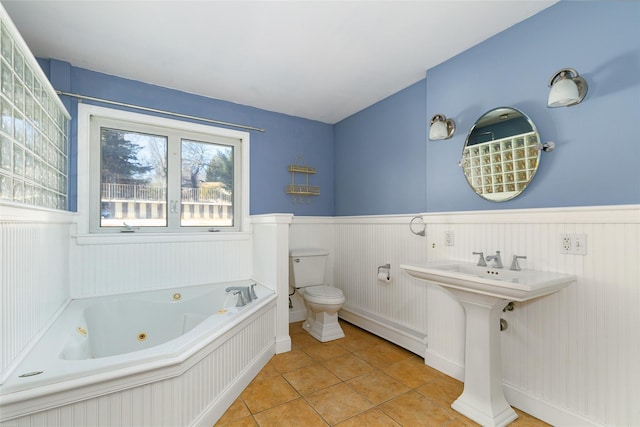 bathroom featuring tile patterned floors, toilet, a tub to relax in, and a baseboard radiator