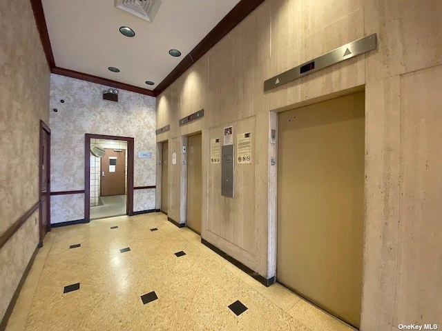 hall with ornamental molding, a high ceiling, and elevator