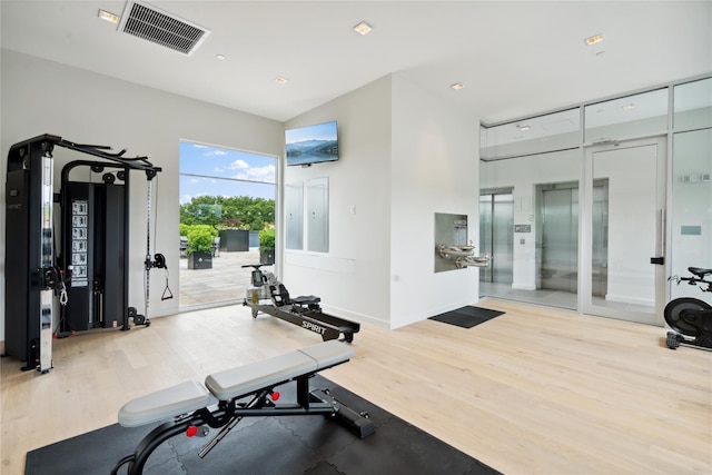 workout area with light wood-type flooring and elevator