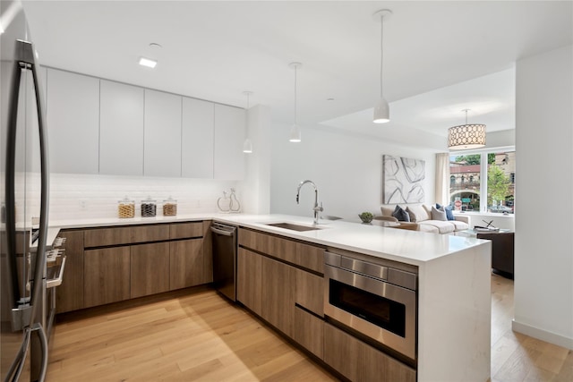 kitchen with stainless steel appliances, sink, pendant lighting, light hardwood / wood-style floors, and white cabinetry