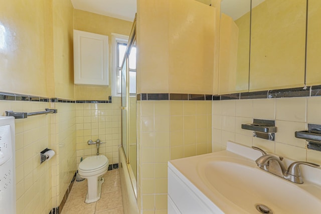 bathroom featuring vanity, a shower with door, tile patterned flooring, toilet, and tile walls