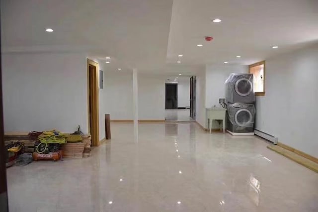 basement featuring stacked washer / dryer, sink, and a baseboard heating unit