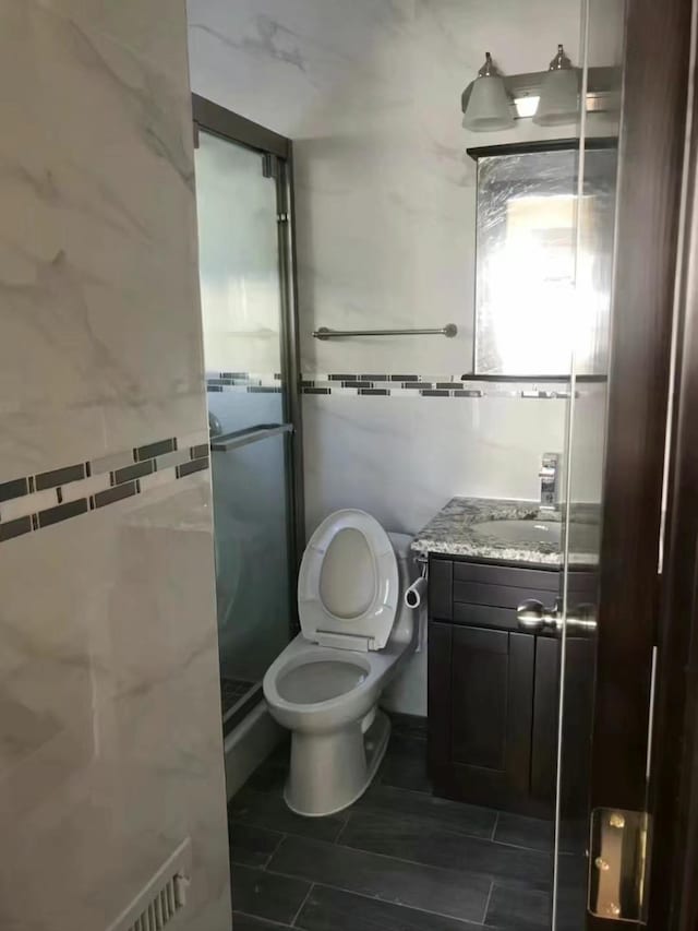 bathroom featuring tile patterned floors, toilet, vanity, and walk in shower