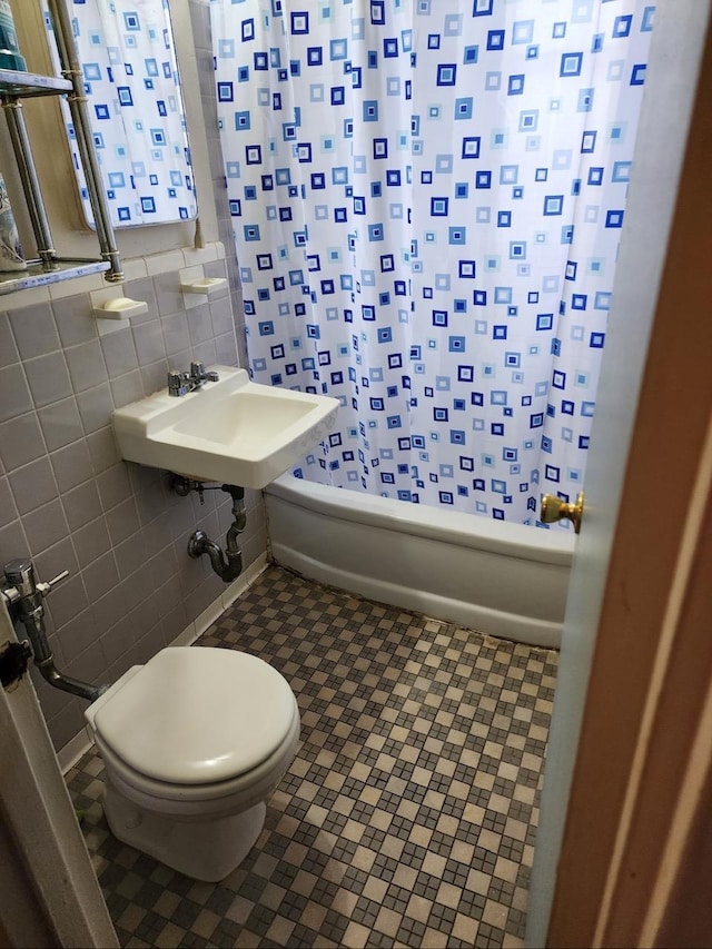 full bathroom featuring toilet, sink, tile walls, shower / bathtub combination with curtain, and tile patterned flooring