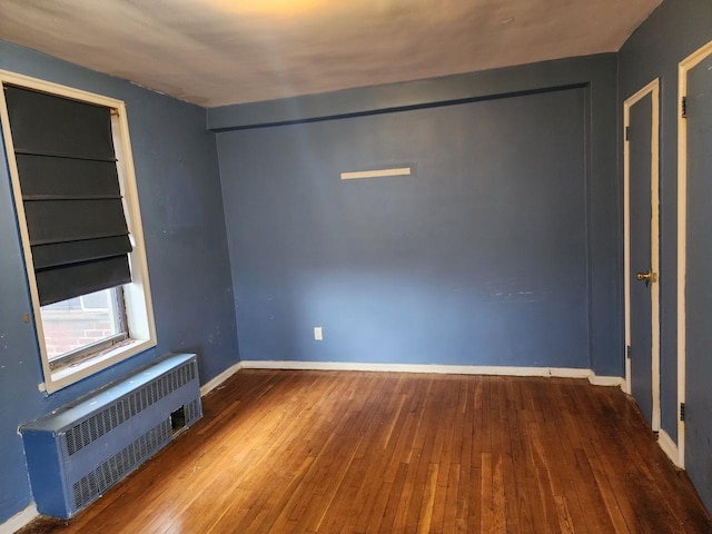 empty room featuring hardwood / wood-style flooring and radiator heating unit