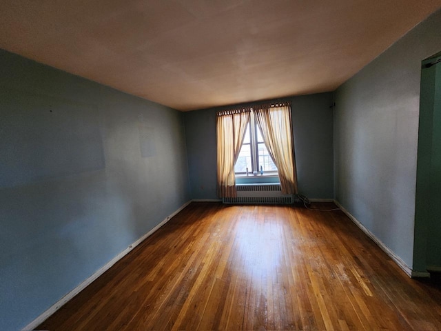 spare room featuring dark hardwood / wood-style floors and radiator