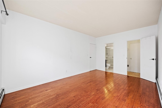 unfurnished bedroom with connected bathroom, hardwood / wood-style floors, and a baseboard radiator