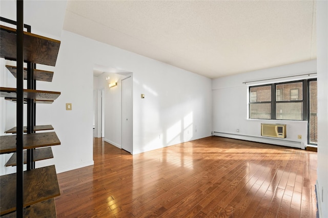 unfurnished living room with a baseboard radiator, an AC wall unit, and hardwood / wood-style flooring