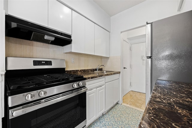 kitchen with sink, dark stone countertops, light tile patterned floors, white cabinetry, and stainless steel appliances