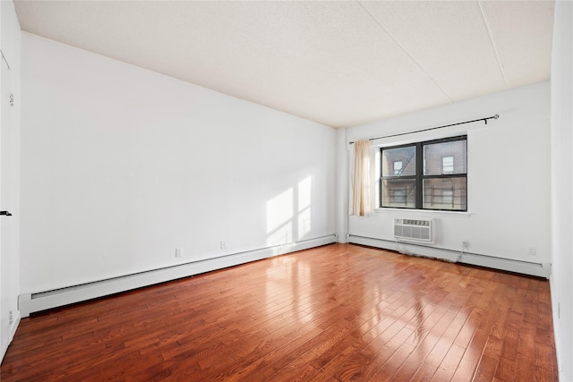 spare room featuring hardwood / wood-style floors, a wall unit AC, and a baseboard radiator