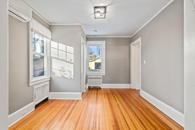 spare room with a wall mounted air conditioner, light wood-type flooring, crown molding, and radiator