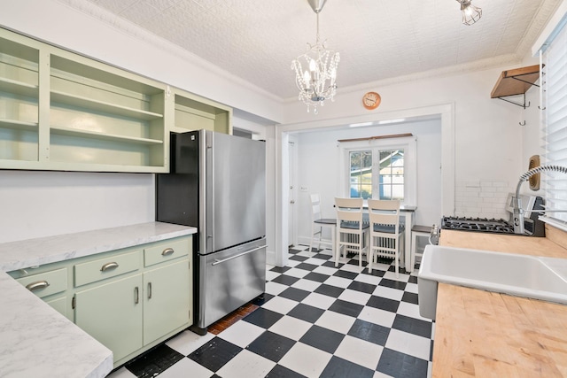 kitchen featuring stainless steel fridge, ornamental molding, decorative light fixtures, a chandelier, and green cabinets