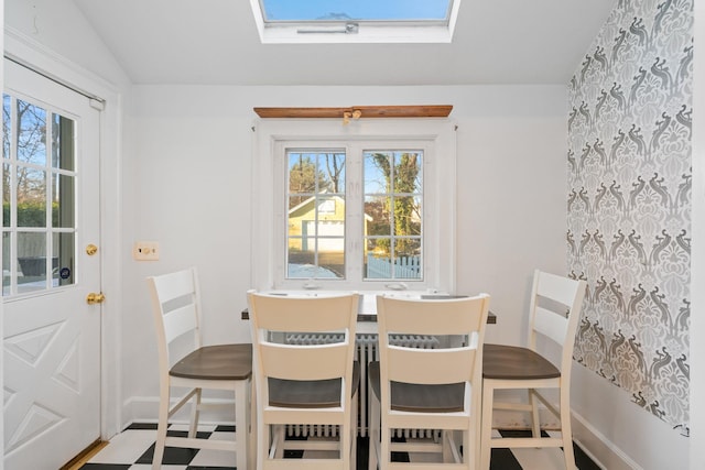 dining space with lofted ceiling with skylight