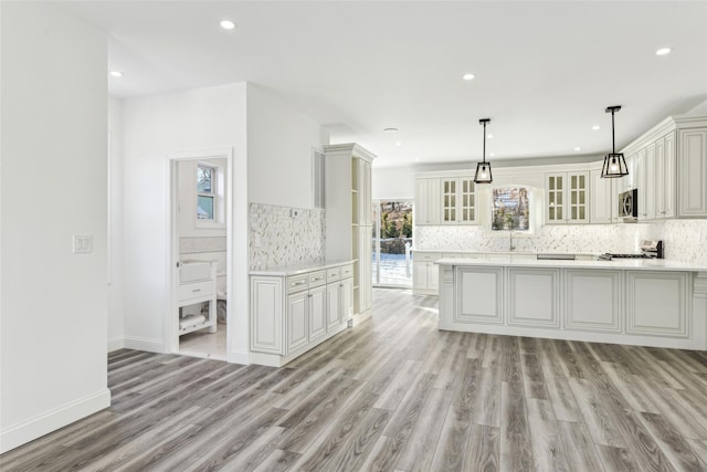 kitchen featuring tasteful backsplash, light hardwood / wood-style floors, hanging light fixtures, and sink