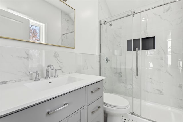 bathroom with decorative backsplash, vanity, a shower with door, tile walls, and toilet