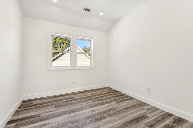 unfurnished room with hardwood / wood-style flooring and vaulted ceiling