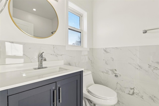 bathroom featuring vanity, toilet, and tile walls