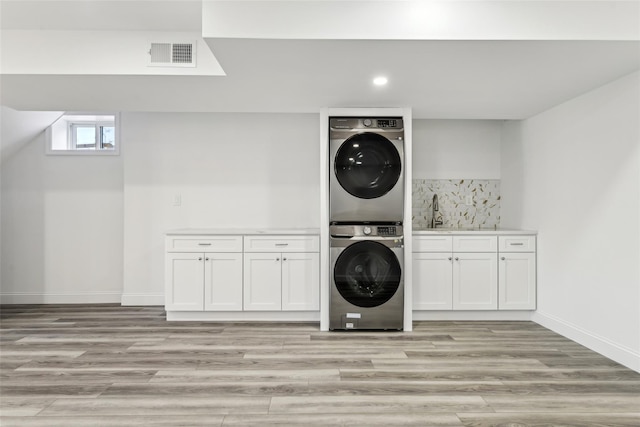 washroom with stacked washer and dryer, light hardwood / wood-style floors, and sink