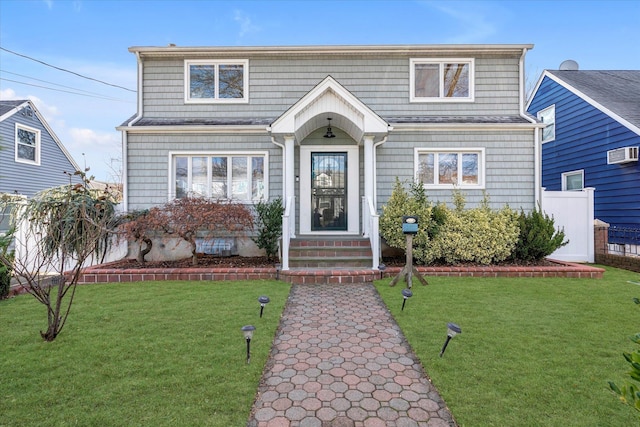 view of front of home with a front yard and a wall unit AC