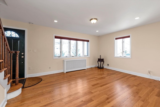 interior space featuring plenty of natural light, radiator heating unit, and light hardwood / wood-style flooring