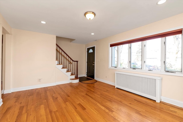 foyer entrance with light hardwood / wood-style floors and radiator heating unit