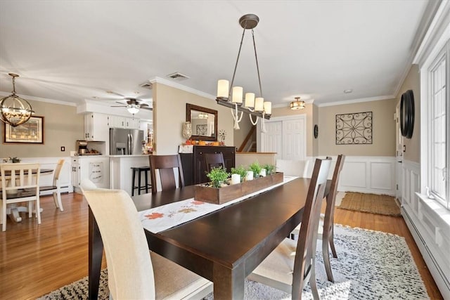 dining room with crown molding, a baseboard radiator, ceiling fan with notable chandelier, and light hardwood / wood-style floors