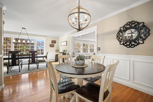 dining space featuring light hardwood / wood-style flooring, an inviting chandelier, and crown molding