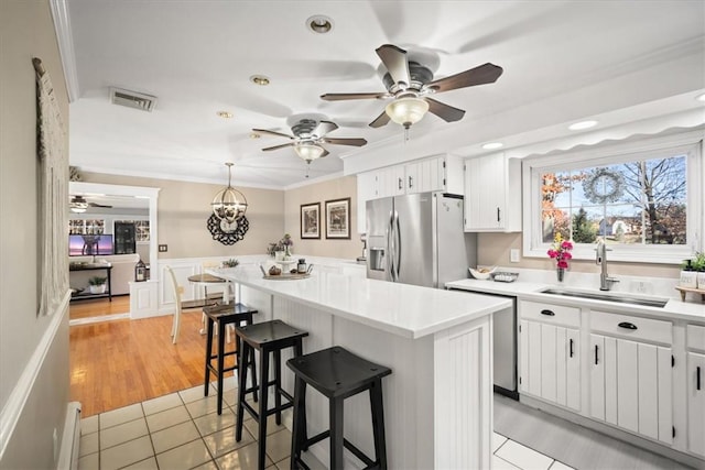 kitchen with sink, hanging light fixtures, light tile patterned floors, white cabinetry, and stainless steel appliances