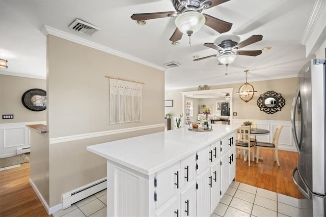 kitchen with stainless steel fridge, white cabinetry, baseboard heating, and light tile patterned flooring