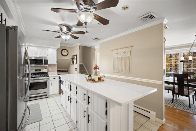 kitchen with appliances with stainless steel finishes, ornamental molding, a baseboard heating unit, white cabinetry, and a kitchen island