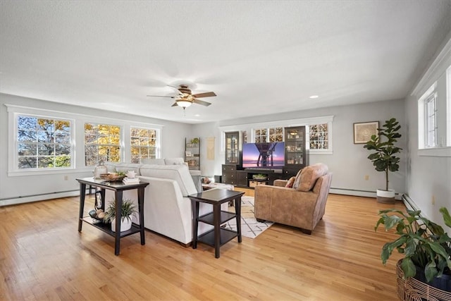 living room with baseboard heating, ceiling fan, and light hardwood / wood-style floors