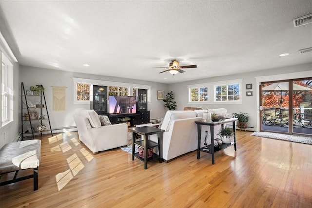 living room with ceiling fan, light hardwood / wood-style flooring, and a textured ceiling