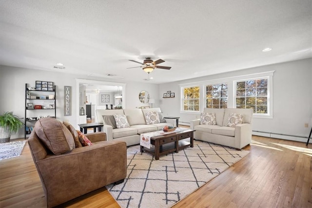 living room featuring baseboard heating, ceiling fan, and light wood-type flooring