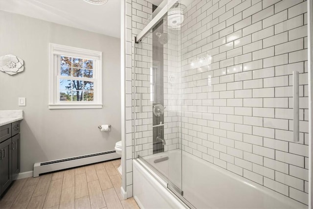 full bathroom featuring hardwood / wood-style floors, vanity, a baseboard heating unit, toilet, and enclosed tub / shower combo