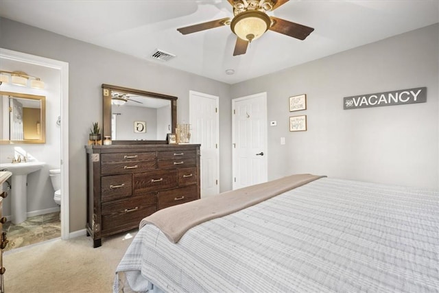 carpeted bedroom with ensuite bathroom and ceiling fan